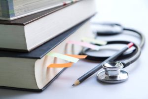 Medical student textbooks with pencil and multicolor bookmarks and stethoscope isolated on white