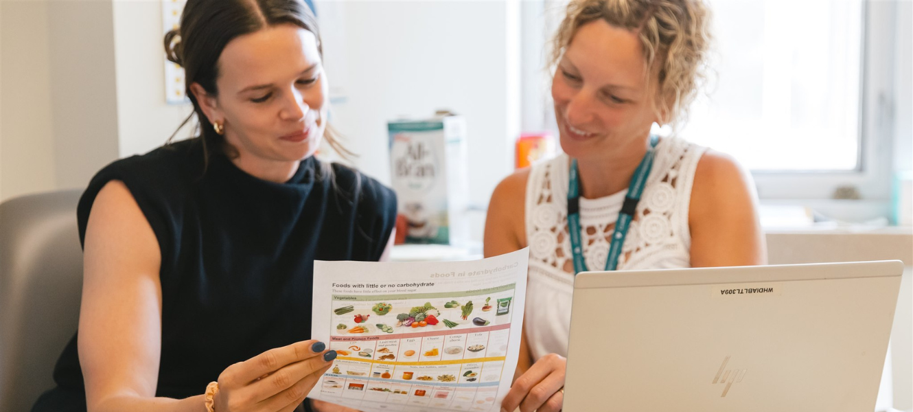 This is a picture of Diabetes Educators looking at an educational form that has different food items and their nutritional benefits.